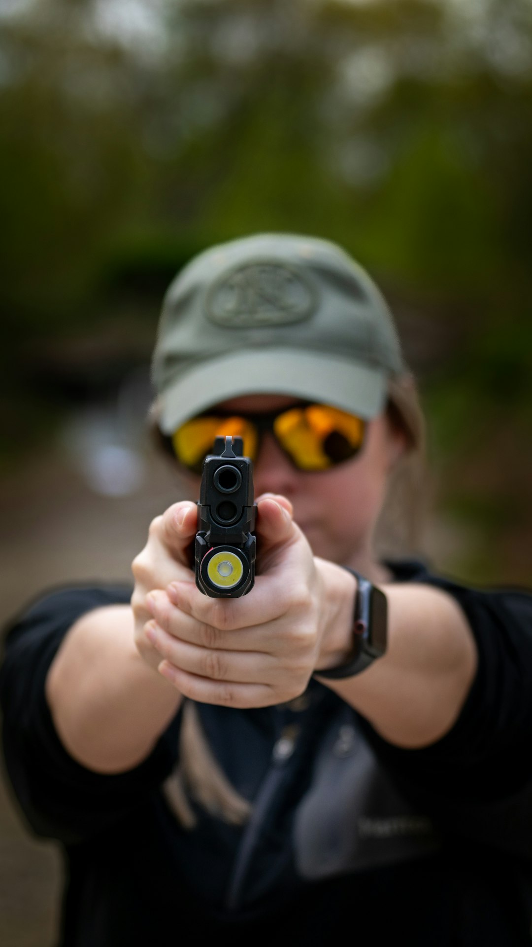our-story a-woman-in-a-hat-and-sunglasses-holding-a-gun-l9aqiikujg