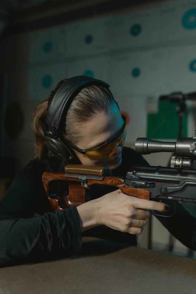 focused-woman-aiming-for-the-target-6090784 Focused woman aiming a rifle during an indoor shooting practice session.