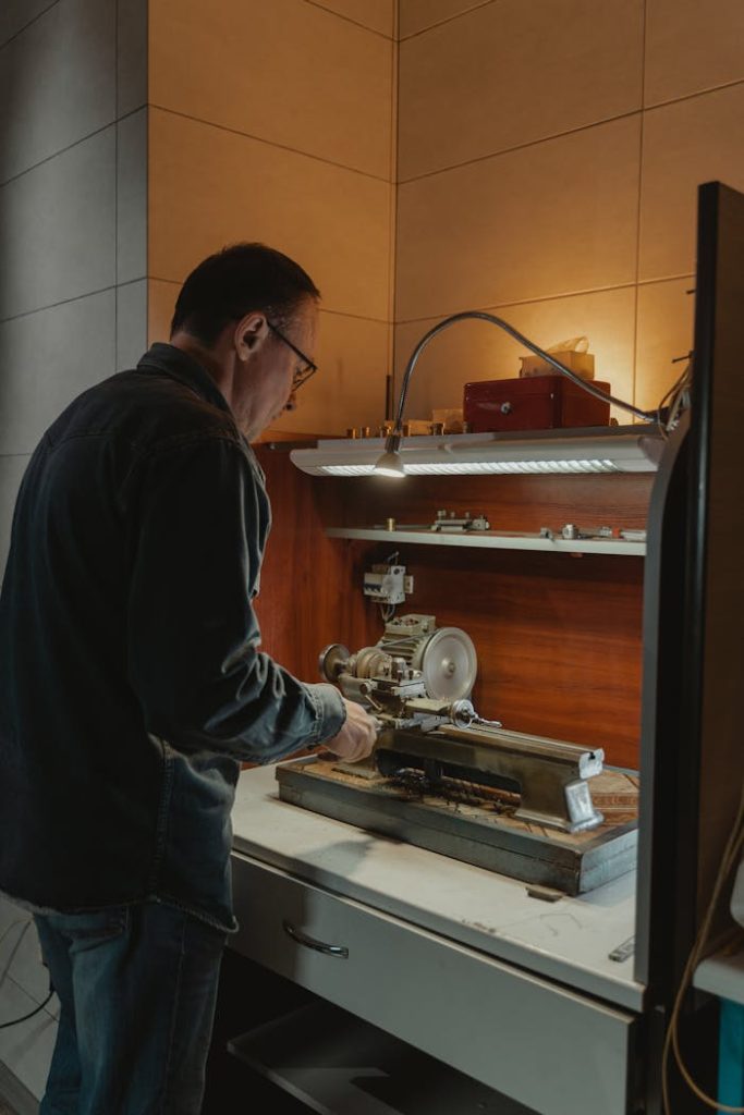 An adult male craftsman using a lathe in a well-lit workshop space.